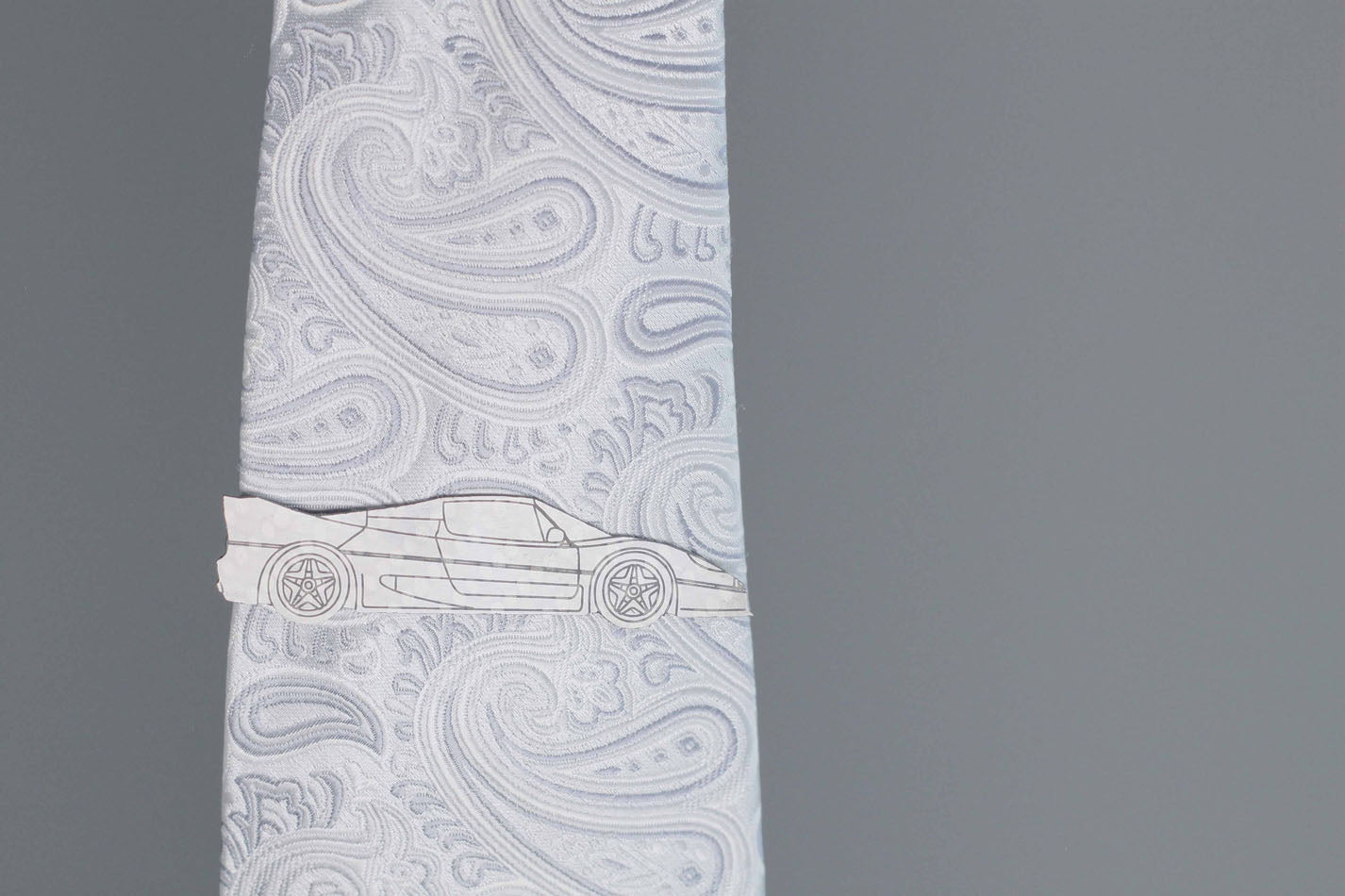 F50 carbon fiber tie clip, reflecting light on a silver tie. Perfect for any car lover.